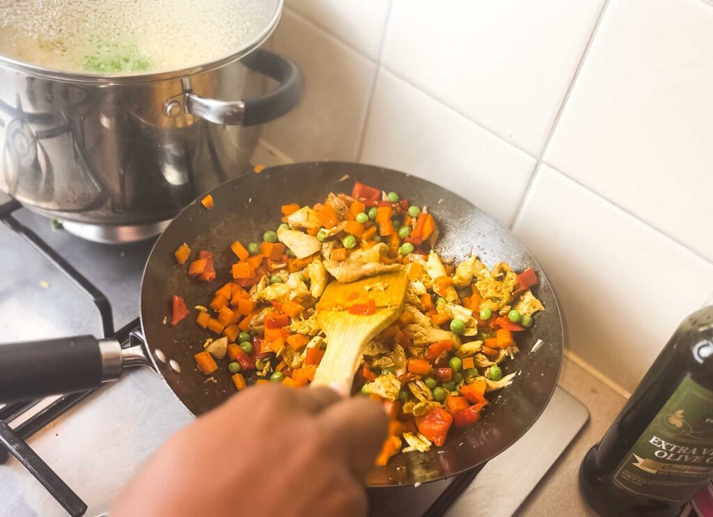 Stir frying vegetables and chicken for nigerian coconut rice 