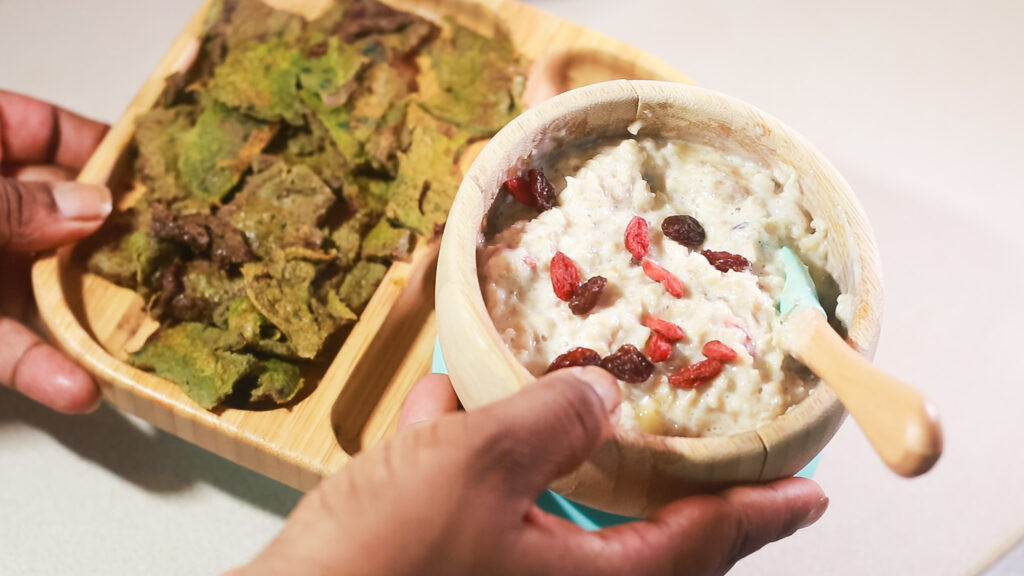 A bowl of toddler porridge oats with banana, goji berries and raisins and a side dish of spinach and beetroot omelette