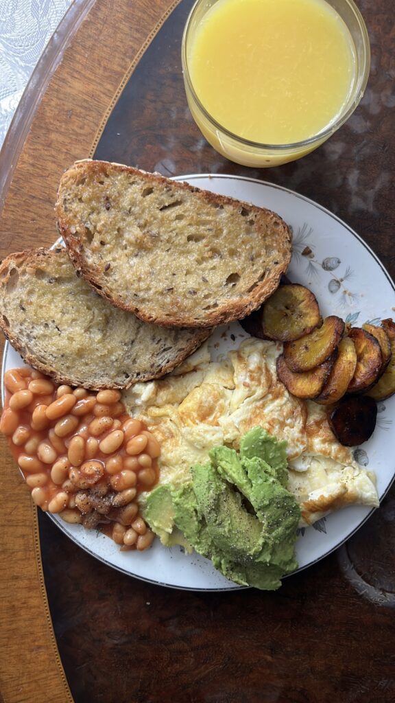 Nigerian breakfast with toast, baked beans, avocado, fried eggs and fried plantain