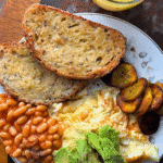 Nigerian breakfast with toast, baked beans, avocado, fried eggs and fried plantain