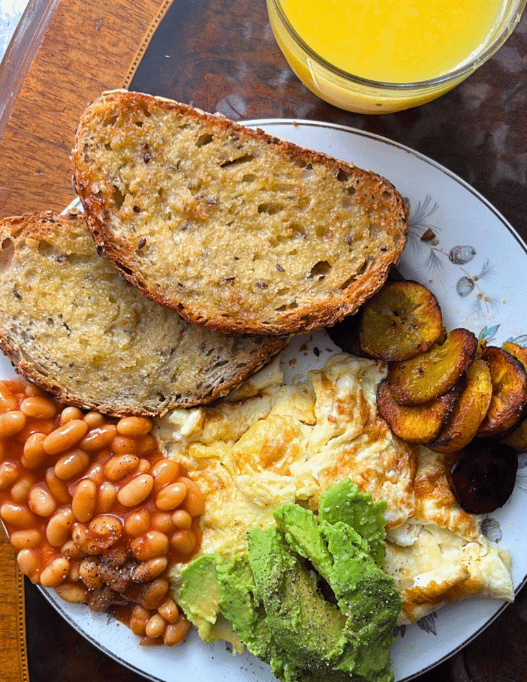 Nigerian breakfast with toast, baked beans, avocado, fried eggs and fried plantain